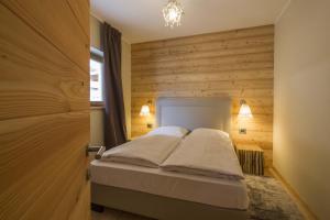 a bedroom with a bed and a wooden wall at Residence Aspen in Arabba