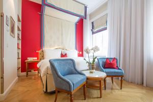 a bedroom with a bed and two blue chairs at Hotel Kaiserhof Wien in Vienna