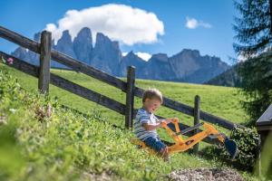 a little boy sitting next to a fence playing with a toy vehicle at Apartment Mittermanting in Villnoss