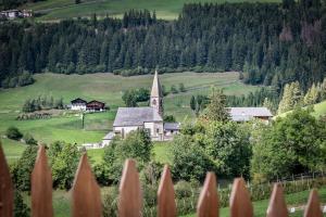 a church in the middle of a green field at Apartment Mittermanting in Villnoss