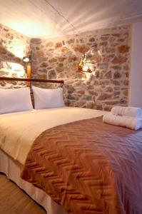 1 dormitorio con 1 cama grande y pared de piedra en Braxos A beautiful rocky place, en Hydra