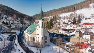 een kerk met een toren in een stad in de sneeuw bij Apartmán Albreit 1 in Jáchymov