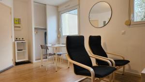 a living room with a table and chairs and a mirror at Studio calme proche centre in Reims