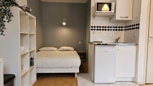 a small room with a bed and a kitchen at Studio calme proche centre in Reims