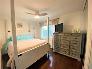 a bedroom with a bed and a dresser with a television at Bay Beach Bungalow in San Diego