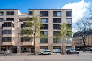 un grand bâtiment en briques avec des voitures garées devant lui dans l'établissement CITY STAY - Franklinstrasse, à Zurich