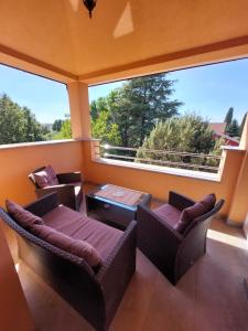 een balkon met 2 stoelen, een tafel en een groot raam bij Lana in Fažana