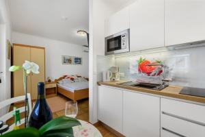 una cucina con armadi bianchi e una camera con un letto di Guesthouse Casa Nova a Poreč (Parenzo)