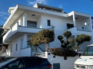 un bâtiment blanc avec des voitures garées devant lui dans l'établissement Fronte mare, à Cala Gonone