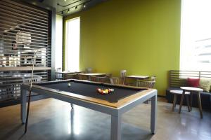 a billiard table in a room with tables and chairs at Alt Hotel Toronto Airport in Mississauga