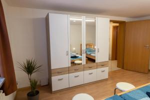 a bedroom with a large white cabinet with a mirror at Ferienwohnung am Bach in Oberkotzau