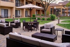 un patio con tavoli, sedie e ombrellone di Courtyard Detroit Dearborn a Dearborn