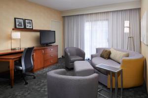 una camera d'albergo con divano, scrivania e TV di Courtyard Detroit Dearborn a Dearborn