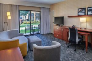 una camera d'albergo con scrivania e TV di Courtyard Detroit Dearborn a Dearborn