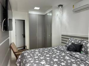 1 dormitorio con 1 cama con edredón blanco y negro en Manfrenati Ap, en Cabo Frío