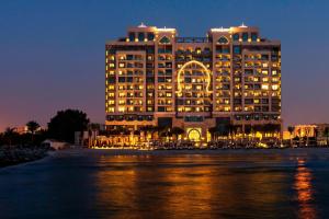 ein großes Gebäude mit einem nachts beleuchteten Bogen in der Unterkunft Ajman Saray, a Luxury Collection Resort, Ajman in Ajman 