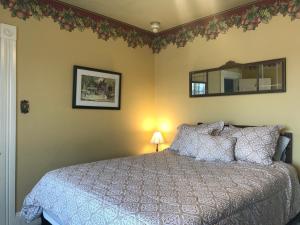 um quarto com uma cama e um espelho na parede em The Maple Inn em Parrsboro