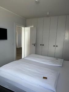 een witte slaapkamer met een groot bed en witte kasten bij Strandhotel in Wyk auf Föhr