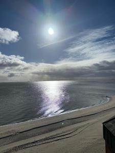 een strand met de zon reflecterend op het water bij Strandhotel in Wyk auf Föhr