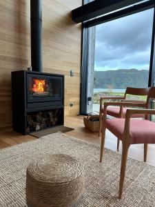 een woonkamer met een open haard en een stoel bij Sete Cidades Lake Cabin - Casa da Lagoa in Ponta Delgada