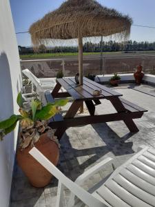 uma mesa de piquenique e cadeiras num pátio com um guarda-sol de palha em Casa Malaquias em Santo André