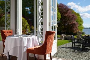 uma mesa num alpendre com vista para a água em Storrs Hall Hotel em Bowness-on-Windermere