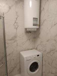 a white washing machine in a bathroom with marble walls at Apartments Domovik Myru St. 11s/21 in Mukacheve