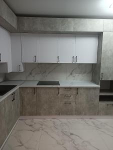 an empty kitchen with white cabinets and marble floors at Apartments Domovik Myru St. 11s/21 in Mukacheve