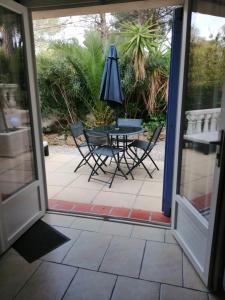 een patio met een tafel en stoelen en een parasol bij L'esterel in Fréjus