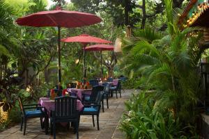 eine Reihe von Tischen und Stühlen mit roten Sonnenschirmen in der Unterkunft Bumi Surabaya City Resort in Surabaya