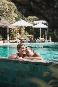 un homme et une femme dans une piscine dans l'établissement Uluwatu Cottages, à Uluwatu