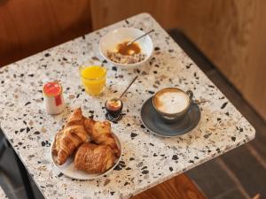 uma mesa com um pequeno-almoço de croissants e uma chávena de café em Eklo Lyon em Vénissieux