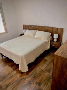 una camera da letto con letto, lenzuola bianche e pavimenti in legno di Casa pet friendly, se reserva con seña a Piriápolis