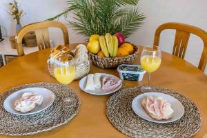 uma mesa de madeira com pratos de comida e copos de sumo de laranja em Terraços do Vau 108 em Portimão