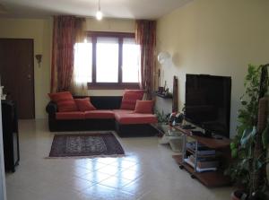 uma sala de estar com um sofá vermelho e uma televisão em Sweet Sardinia Apartment R2968 em Elmas