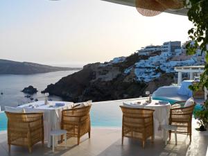 a table with chairs and a view of the ocean at Katikies Santorini - The Leading Hotels Of The World in Oia