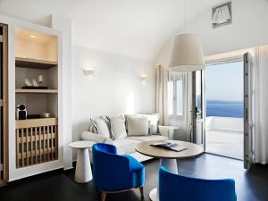 a living room with a couch and a table and chairs at Katikies Santorini - The Leading Hotels Of The World in Oia