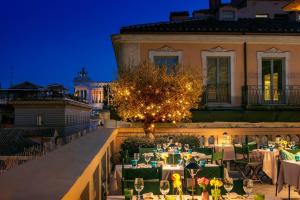 eine Gruppe von Tischen und Stühlen auf einem Balkon in der Nacht in der Unterkunft Singer Palace Hotel Roma in Rom