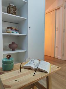 un tavolo di legno con un libro e degli occhiali di Wood Essence Apartment - Cozy Balcony a Coimbra