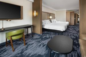 a hotel room with two beds and a desk and a tv at Fairfield Inn & Suites by Marriott South Kingstown Newport Area in South Kingstown