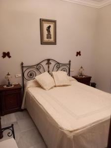 1 dormitorio con 1 cama blanca grande y 2 mesitas de noche en Al ladito de Sevilla, en Bormujos