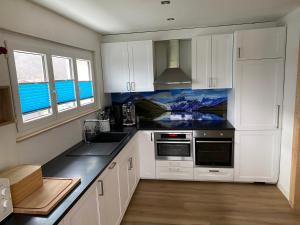 a kitchen with white cabinets and black counter tops at Spring Inn Apartments in Meiringen