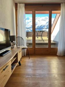 Wengen Apartment - Amazing views, centrally located by train station في ون قن: غرفة بها مكتب مع تلفزيون ونوافذ