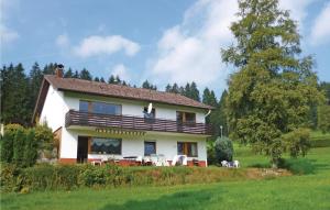 ein großes weißes Haus mit Stühlen und einem Baum in der Unterkunft Gorgeous Apartment In Lenzkirch-Saig With Kitchen in Lenzkirch