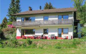 ein großes weißes Haus mit roten Stühlen und Tischen in der Unterkunft Gorgeous Apartment In Lenzkirch-Saig With Kitchen in Lenzkirch