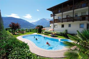 un gruppo di persone in una piscina accanto a un edificio di Feldhof Schenna a Scena