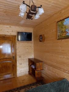 Habitación en una cabaña de madera con TV y banco en Котедж "Затишний відпочинок", en Huklyvyy