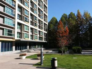 un grande edificio con un albero di fronte di Beijing Yasmine Seasons Park Apartment Hotel a Pechino