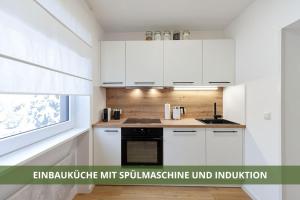 una cucina con armadi bianchi, lavandino e finestra di Die Fichtelsuite 1-6 Pers Ferienwohnung nahe Ochsenkopf Süd 800m in Fleckl a Warmensteinach