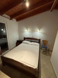 ein Schlafzimmer mit einem Bett und einem Stuhl darin in der Unterkunft Alex Bar APARTMENTS SARAKINIKO in Parga